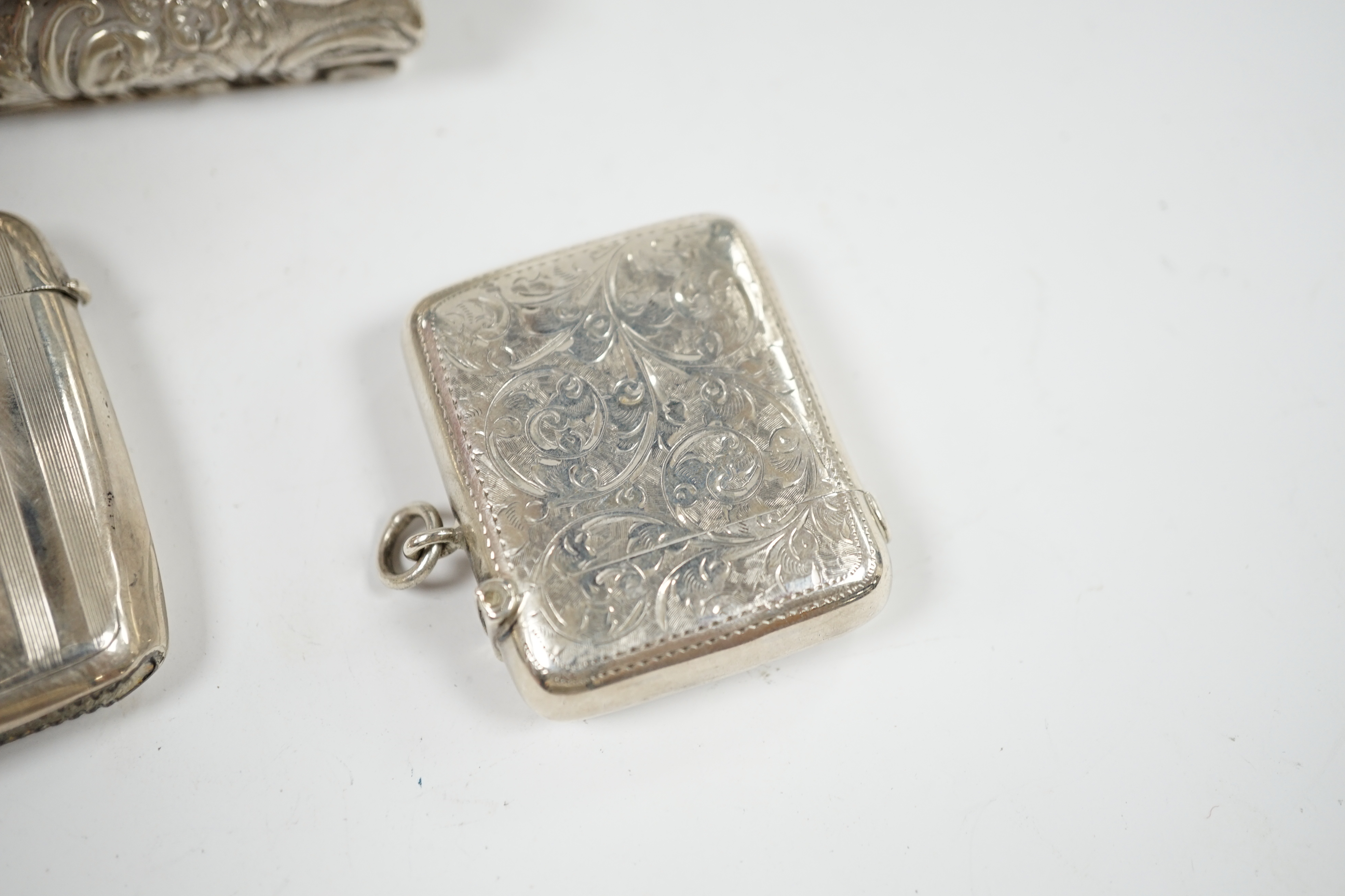 Two early 20th century silver vesta cases and an Edwardian repousse silver trinket box, 11cm. Condition - fair
